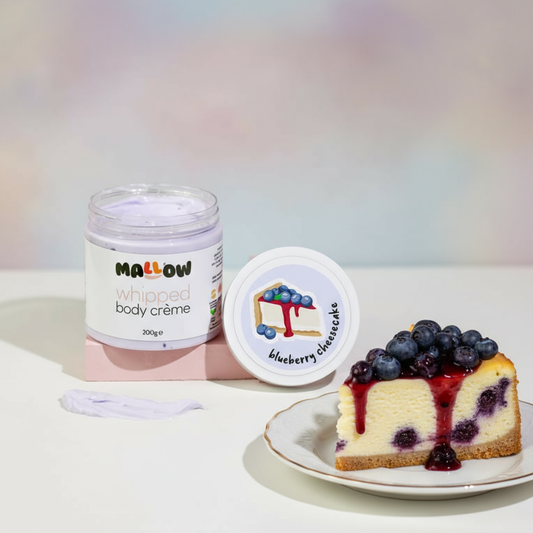 Jar of 'Mallow' whipped body crème and a slice of blueberry cheesecake on a light background