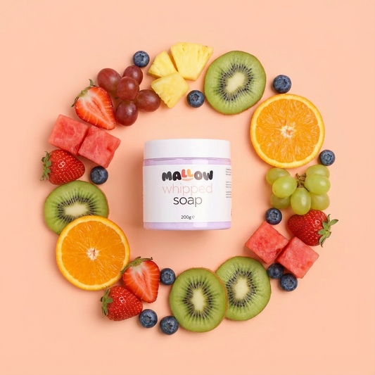 Jar of Mallow Fruit Salad Soap surrounded by a circle of fruits on a peach background